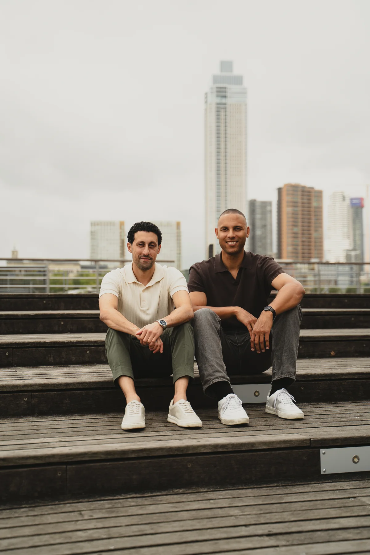 De twee oprichters van WAINUT op een houten trap in Rotterdam.